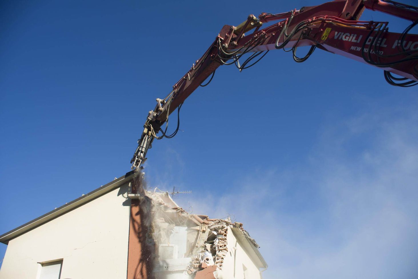 Large machine cutting up a house on a residential demolition site