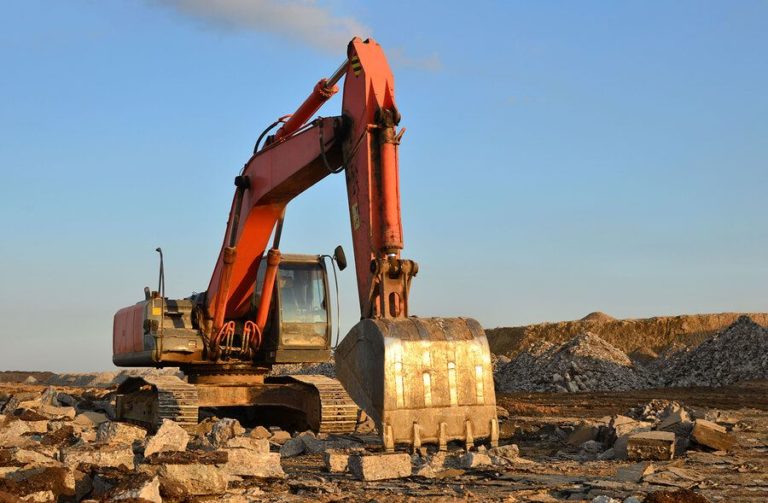 Large excavator organising residential demolition waste on a recycling site