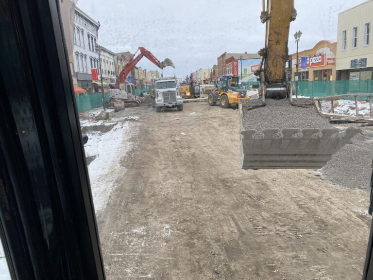 excavators, bulldozers and trucks moving soil and gravel in preparation for the construction of a new parking lot