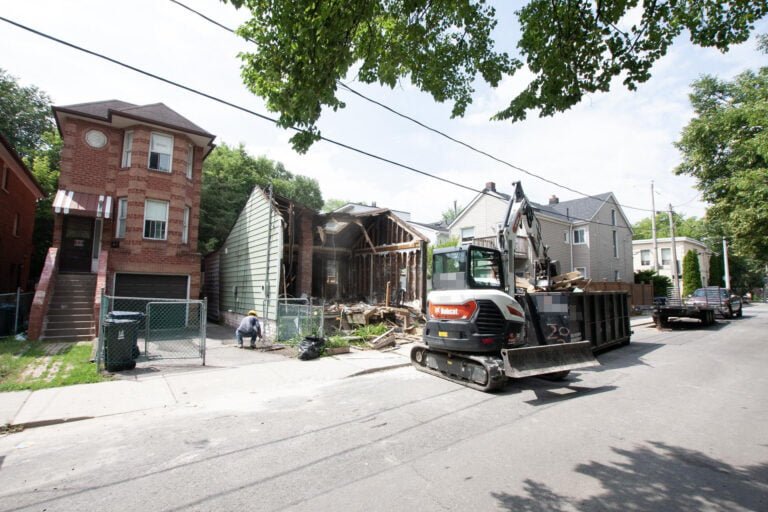 worker and excavator removing debris during the demolition of a home