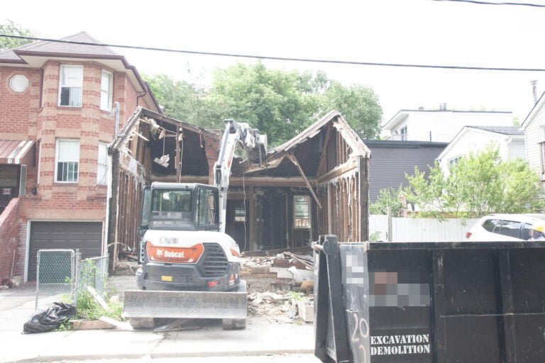 excavator taking down the roof of a house