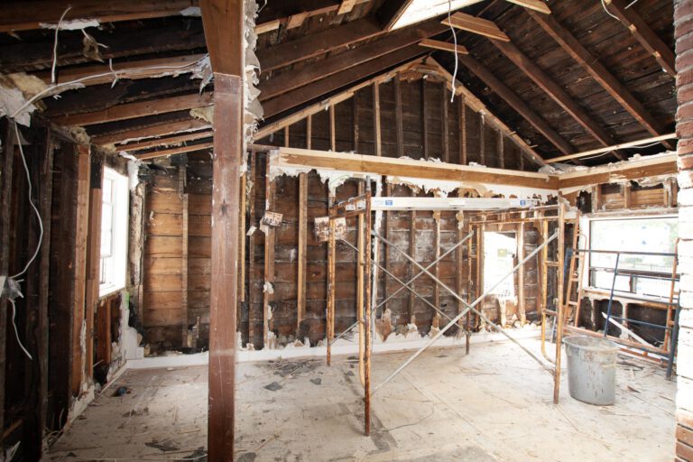 fully stripped ceiling and walls with scaffolding and a small bin for interior demolition waste