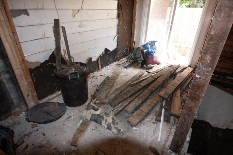 debris leftover from interior demolition, ready to be moved, larger wood pieces on the ground and smaller in a small black bin