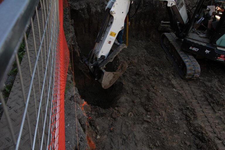 underpinning excavation with an excavator, moving soil out of the way in preparation for future steps