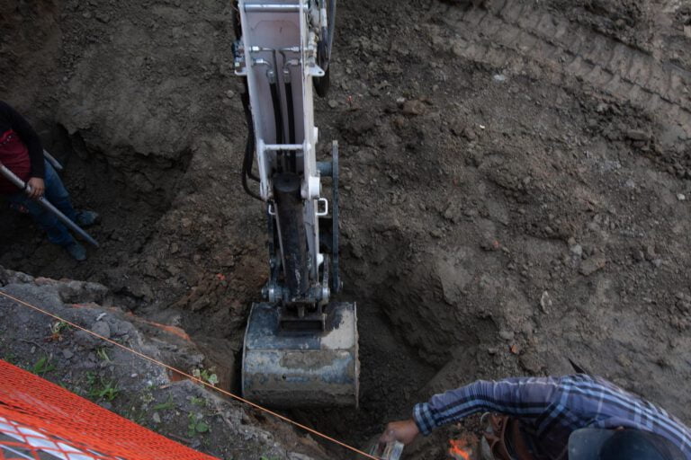 digging holes with an excavator for underpinning and measuring depth with a laser level