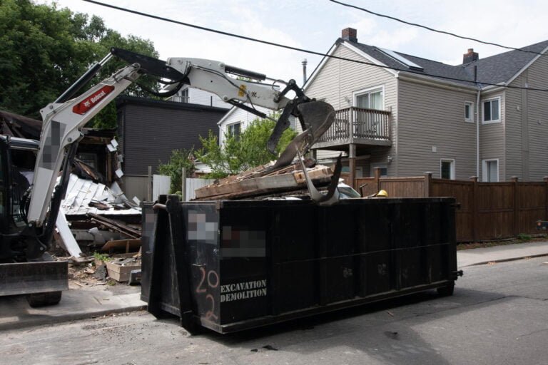 excavator moving demolition debris into a bin